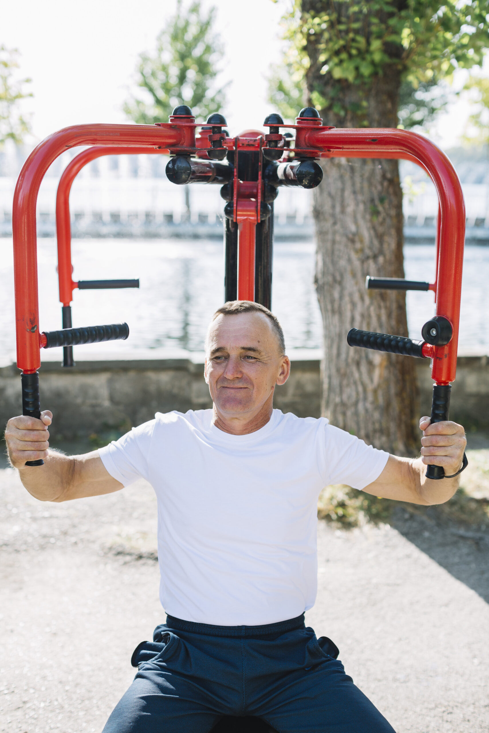 Beginner over 40 performing a seated chest fly on an outdoor gym, multifunctional upper body machine.